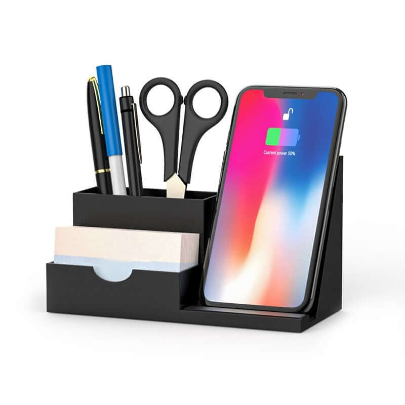 Black wireless charging stand with pen compartment and card slot, shown with a phone and stationery