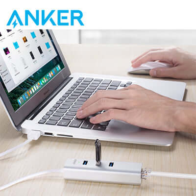 Anker USB and Ethernet hub connected beside a laptop on a desk, illustrating peripheral use.