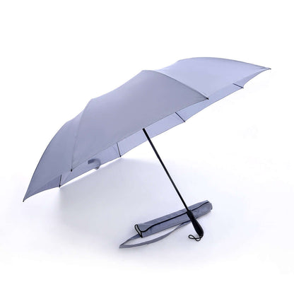 Outer canopy view of the open light-colour golf umbrella beside its carry sleeve with shoulder strap.