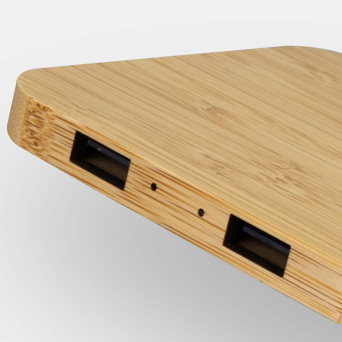 Close-up of the NATURA bamboo charging hub edge showing twin USB-A ports and two small indicator openings