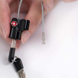 Crossing TSA Travel Cable Lock With Keys in a hand, showcasing a durable design and security features.