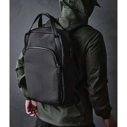 ALPAKA Bravo Tote Pack being worn by a person with a black backpack, showcasing its sleek design and versatility.
