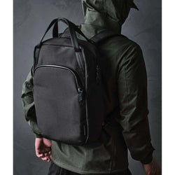 ALPAKA Bravo Tote Pack being worn by a person with a black backpack, showcasing its sleek design and versatility.