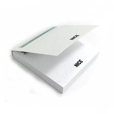 White covered note pad partly opened, showing the note stack and printed cover with a green line and black sample logo