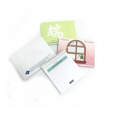 Covered note pad examples with green, pink and white printed covers, with one white pad opened to show notes inside